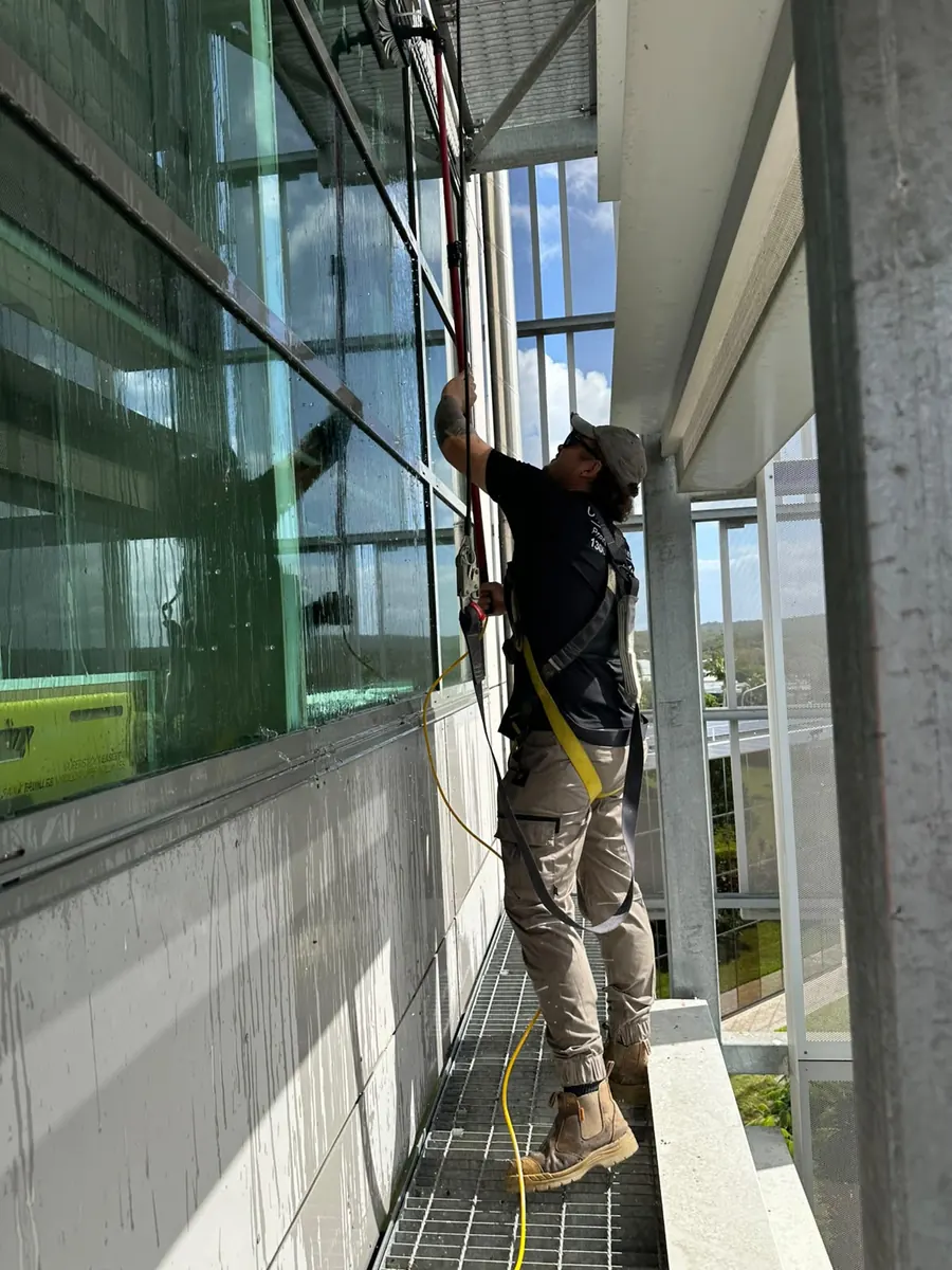 Clean Exteriors technician safely cleaning windows at height, Logan